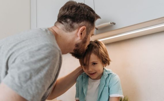Un padre se inclina para hablar con su hijo en la cocina