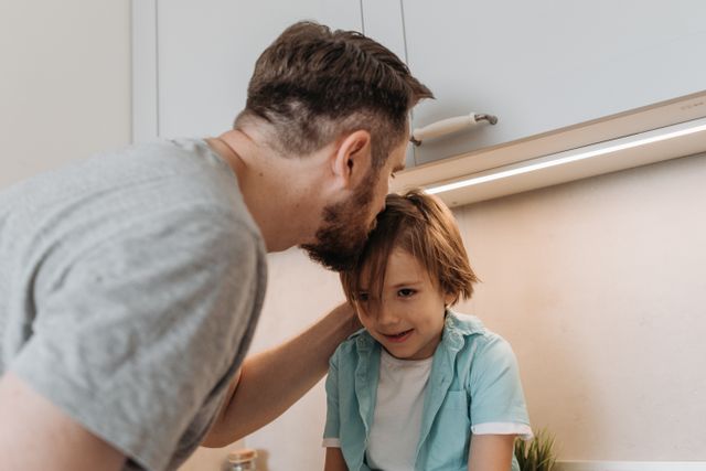Un padre se inclina para hablar con su hijo en la cocina